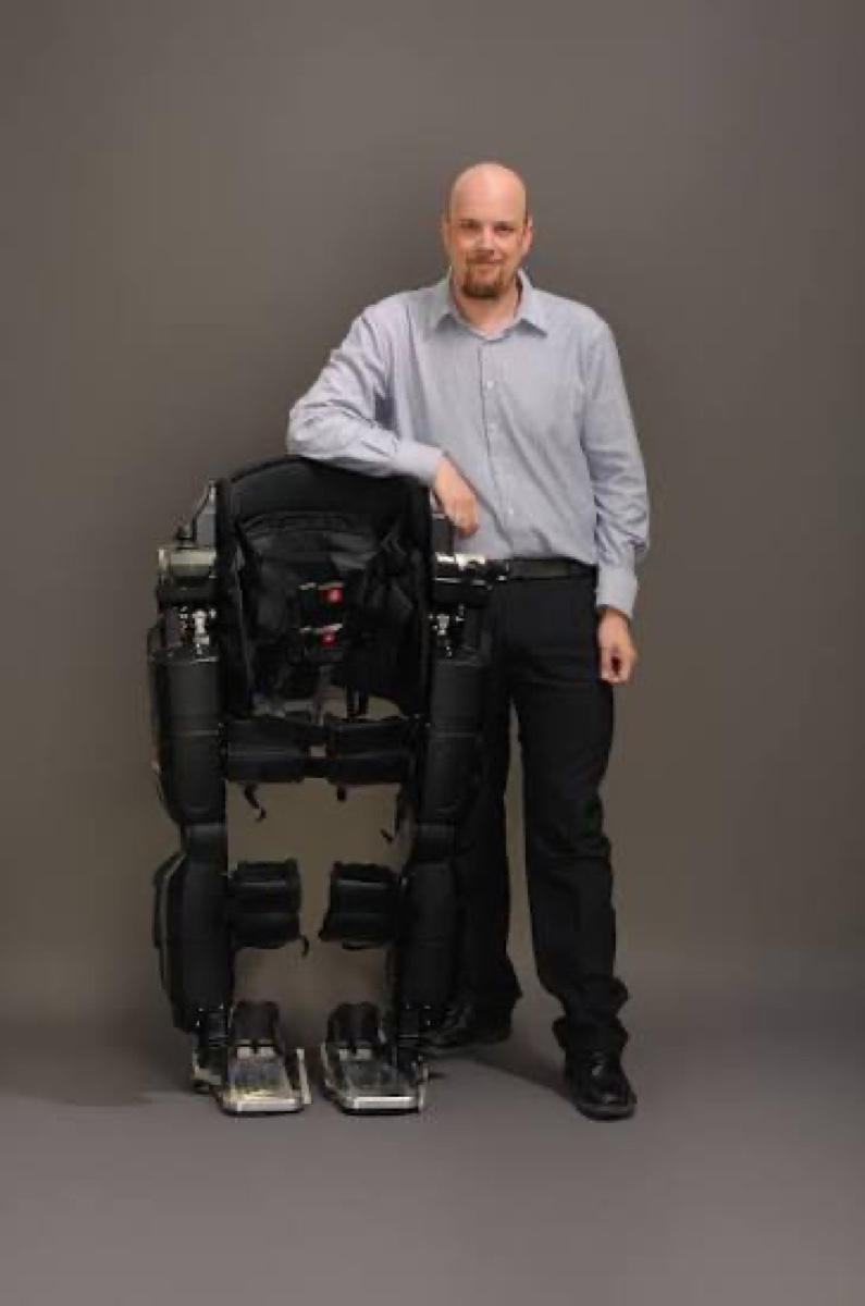 A Globex Engineering team member standing beside a mechanical exoskeleton prototype