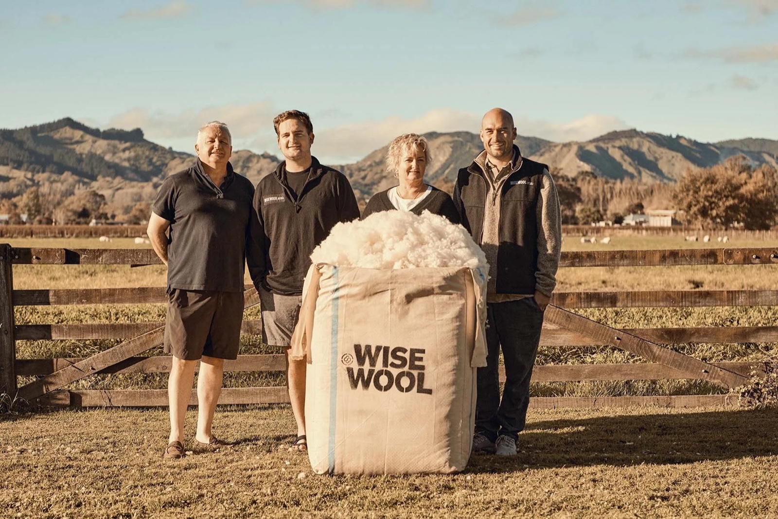 The Wisewool team standing behind a bale of raw wool fibre on a New Zealand farm